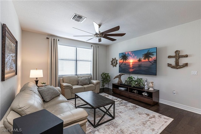 living room with dark wood finished floors, visible vents, a ceiling fan, a textured ceiling, and baseboards