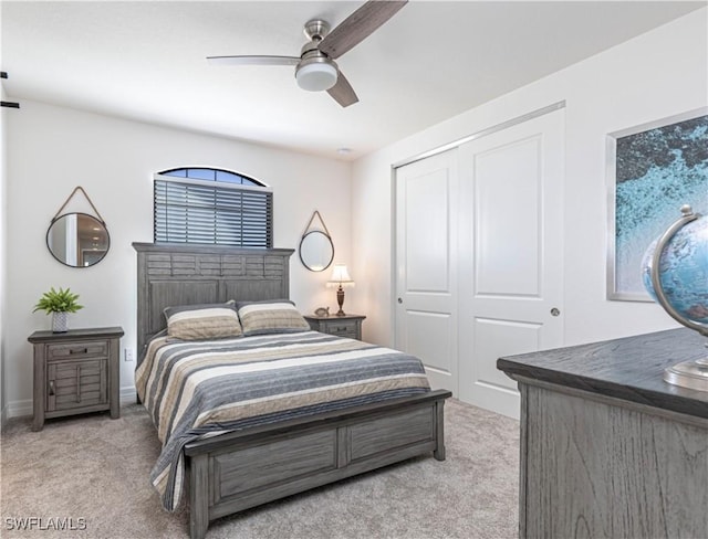 bedroom featuring a ceiling fan, a closet, light carpet, and baseboards