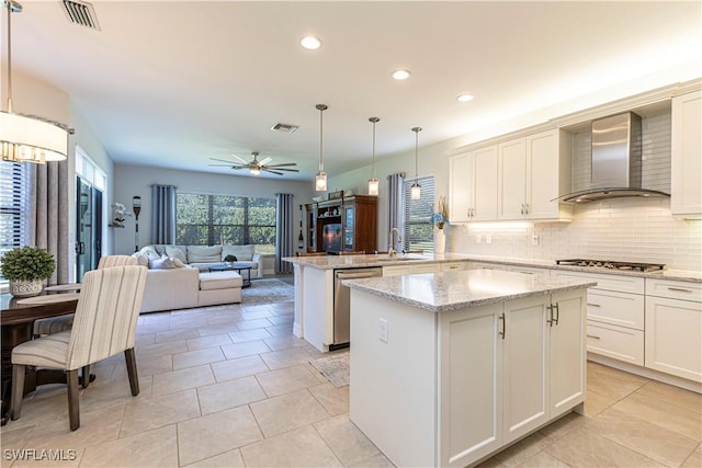 kitchen with appliances with stainless steel finishes, visible vents, a sink, and wall chimney range hood