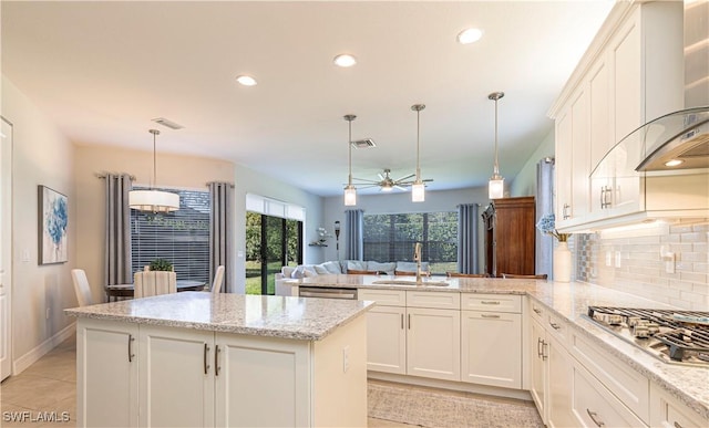 kitchen featuring visible vents, appliances with stainless steel finishes, a peninsula, a sink, and backsplash