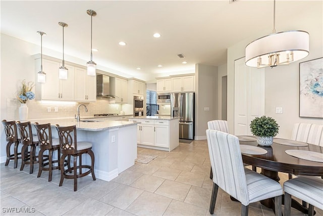 kitchen featuring stainless steel appliances, a peninsula, a kitchen breakfast bar, decorative backsplash, and wall chimney exhaust hood