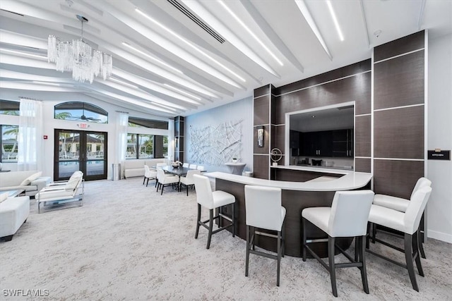 kitchen with french doors, carpet flooring, a notable chandelier, and a kitchen breakfast bar