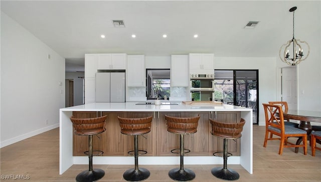 kitchen with a spacious island, decorative backsplash, white fridge, and white cabinets