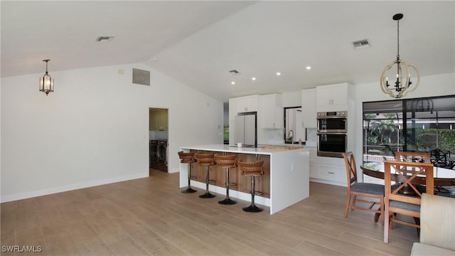 kitchen featuring sink, appliances with stainless steel finishes, a center island, white cabinets, and decorative light fixtures