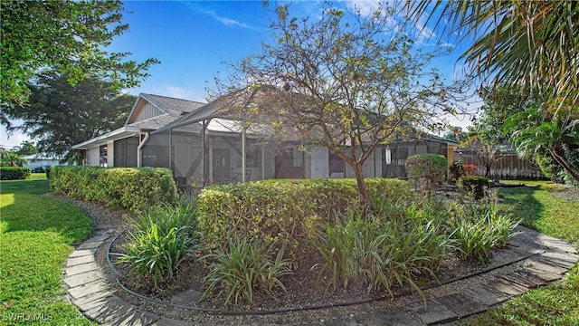 view of side of property featuring glass enclosure and a lawn