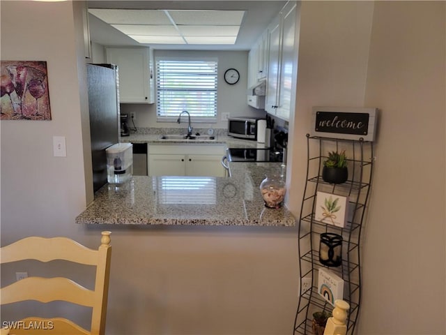 kitchen with light stone counters, appliances with stainless steel finishes, sink, and white cabinets