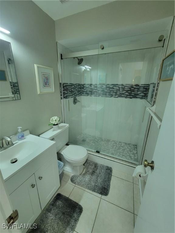 bathroom with tile patterned flooring, toilet, vanity, and a shower with shower door