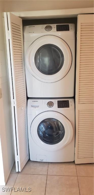 washroom with stacked washer and dryer and light tile patterned floors