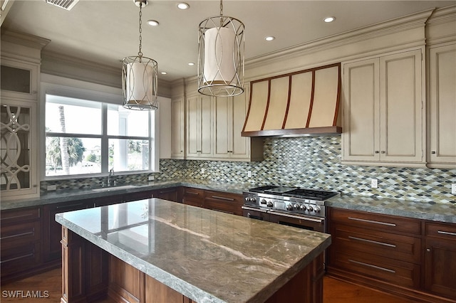 kitchen featuring a kitchen island, light stone countertops, cream cabinetry, and range with two ovens