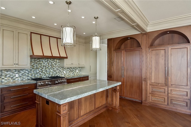 kitchen with range with two ovens, a spacious island, hanging light fixtures, and cream cabinetry