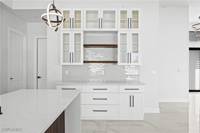 kitchen with pendant lighting, decorative backsplash, light stone countertops, and white cabinets