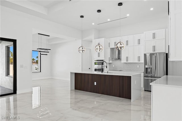 kitchen featuring pendant lighting, stainless steel appliances, an island with sink, and white cabinets