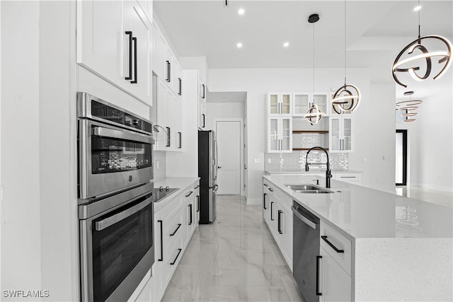 kitchen with pendant lighting, white cabinetry, stainless steel appliances, and a center island with sink