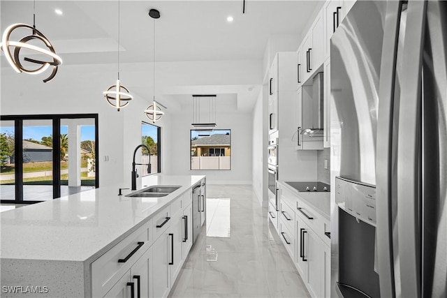 kitchen with white cabinetry, decorative light fixtures, stainless steel fridge, and an island with sink