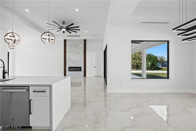 kitchen with white cabinetry, sink, hanging light fixtures, stainless steel dishwasher, and a premium fireplace