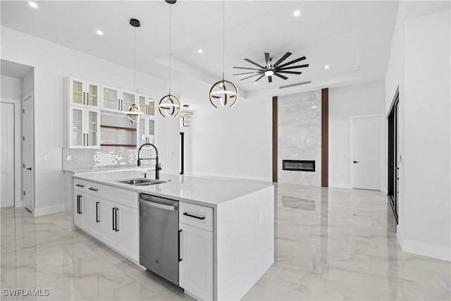 kitchen with white cabinets, a tray ceiling, dishwasher, and a center island with sink