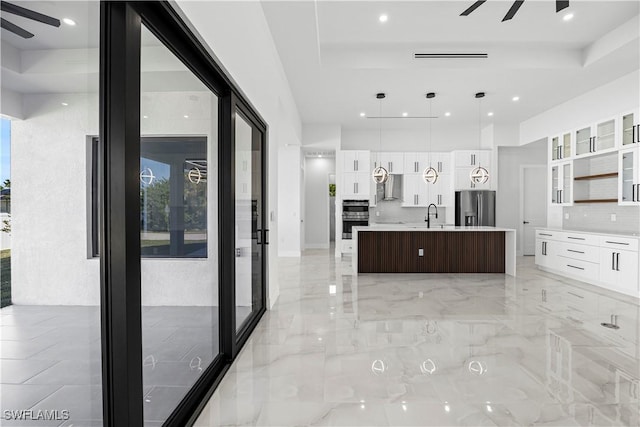 kitchen with white cabinetry, ceiling fan, stainless steel appliances, and an island with sink