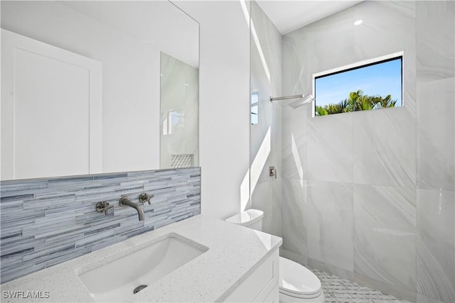 bathroom with tiled shower, vanity, toilet, and decorative backsplash