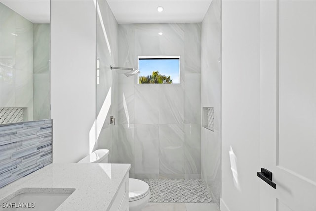 bathroom with vanity, a tile shower, and toilet