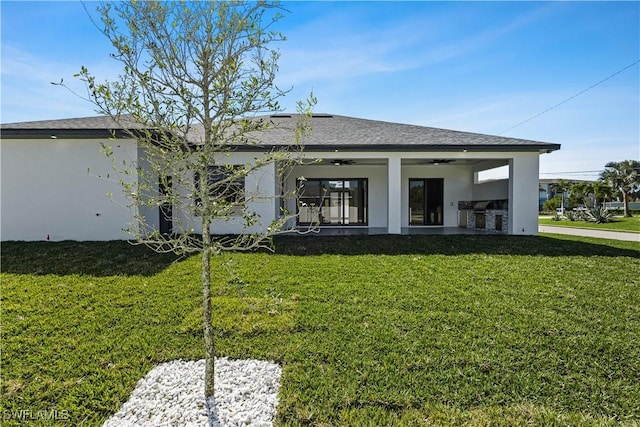 back of house with an outdoor kitchen, ceiling fan, and a lawn