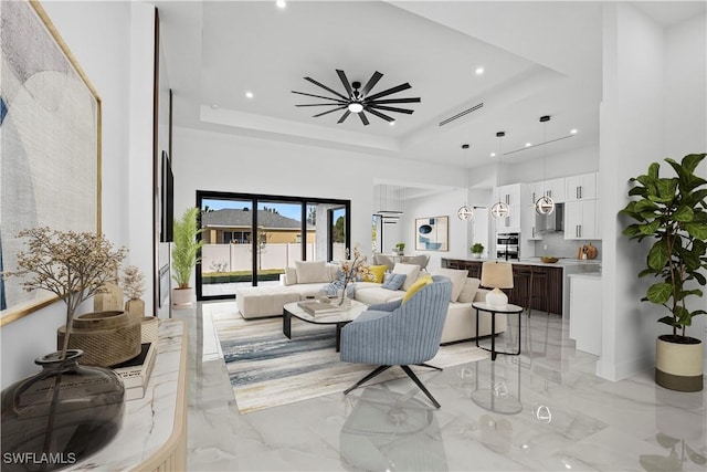 living room with a high ceiling, ceiling fan, and a tray ceiling