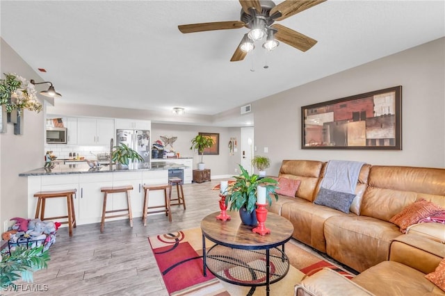 living room featuring ceiling fan and light wood-type flooring