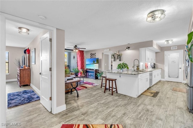 kitchen with a breakfast bar, sink, white cabinets, stainless steel dishwasher, and kitchen peninsula