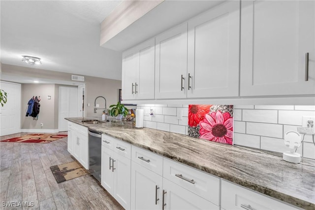 kitchen with stone counters, tasteful backsplash, sink, white cabinets, and light hardwood / wood-style flooring