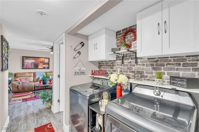 laundry area with cabinets, washing machine and clothes dryer, ceiling fan, and light wood-type flooring