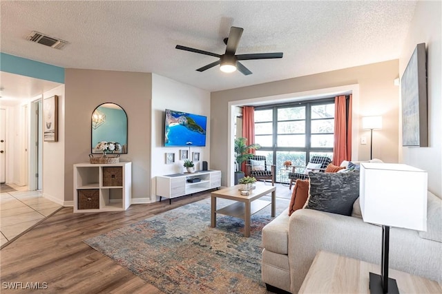 living room with a textured ceiling, wood-type flooring, and ceiling fan