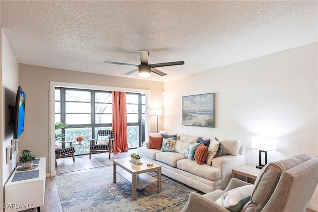 living room with ceiling fan, a textured ceiling, and light wood-type flooring