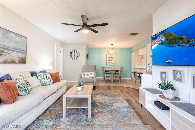 living room featuring dark hardwood / wood-style flooring, ceiling fan, and a textured ceiling