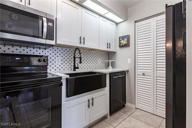 kitchen featuring sink, light tile patterned floors, white cabinetry, tasteful backsplash, and black appliances