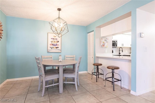 tiled dining room featuring sink, a textured ceiling, and a notable chandelier