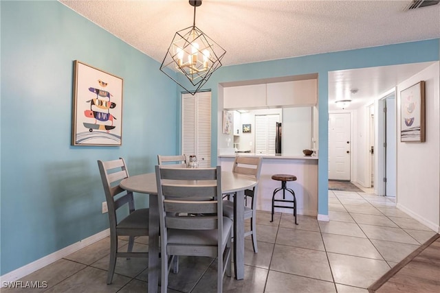 dining area featuring a chandelier, a textured ceiling, and light tile patterned floors