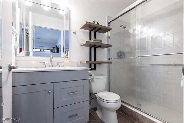 bathroom with walk in shower, tile patterned floors, vanity, and toilet