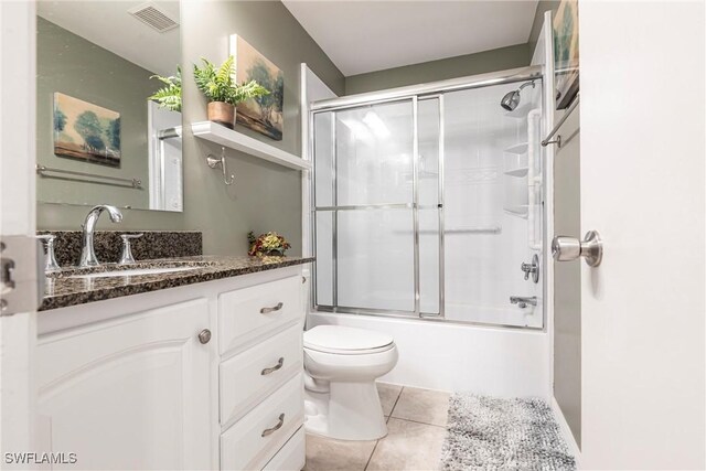 full bathroom featuring vanity, tile patterned floors, shower / bath combination with glass door, and toilet