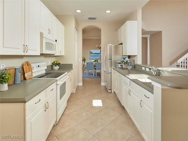 kitchen with light tile patterned floors, white cabinets, white appliances, and kitchen peninsula