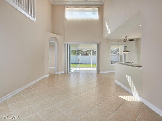 interior space featuring a towering ceiling, ceiling fan, and light tile patterned flooring