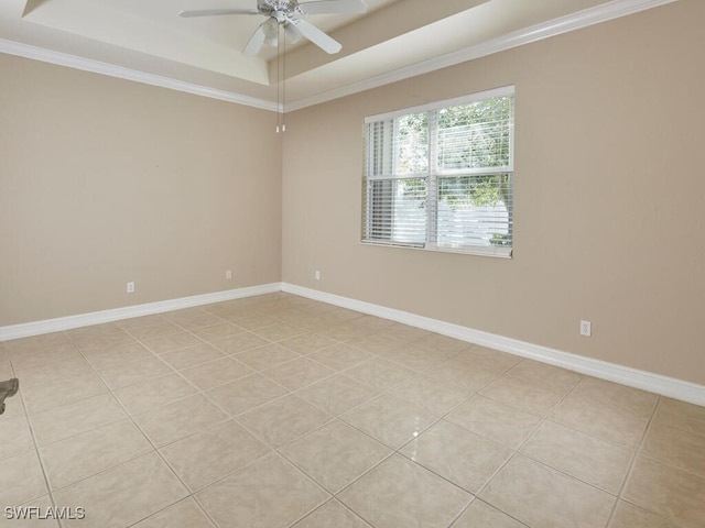 spare room with ceiling fan, ornamental molding, a raised ceiling, and light tile patterned floors