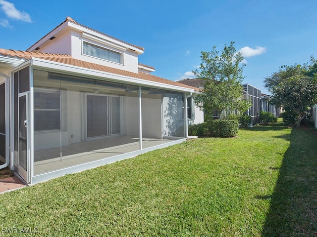 back of property with a lawn and a sunroom