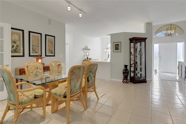 tiled dining space featuring rail lighting and a notable chandelier