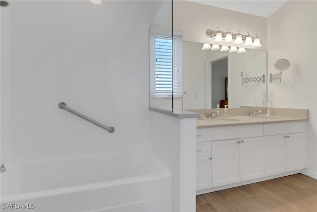 bathroom with vanity, wood-type flooring, and a tub