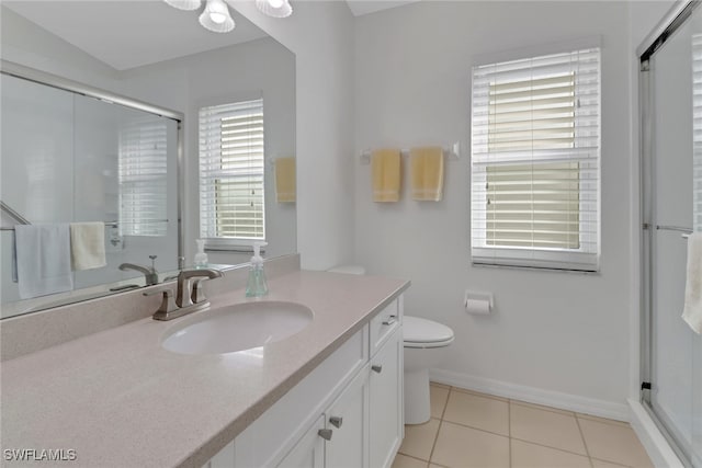 bathroom featuring tile patterned flooring, vanity, toilet, and a shower with shower door