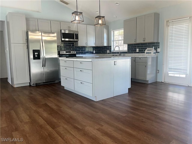 kitchen featuring tasteful backsplash, decorative light fixtures, dark wood-type flooring, and appliances with stainless steel finishes