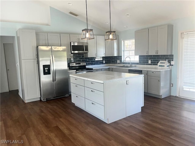 kitchen featuring a kitchen island, appliances with stainless steel finishes, pendant lighting, lofted ceiling, and sink