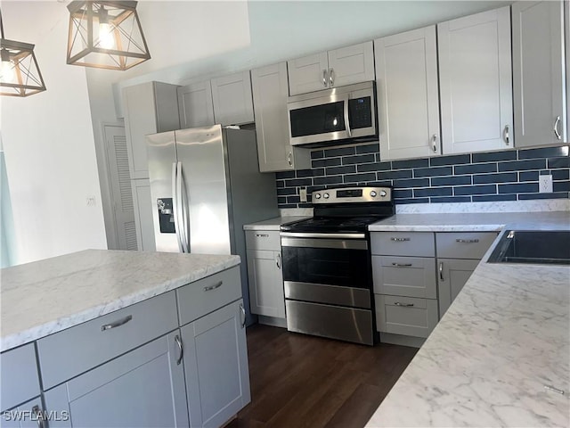 kitchen with sink, appliances with stainless steel finishes, dark hardwood / wood-style flooring, pendant lighting, and backsplash