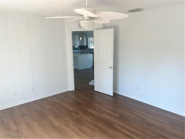 spare room with dark wood-type flooring, ceiling fan, and sink