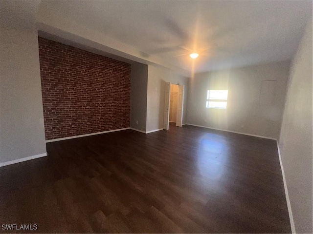 unfurnished room featuring brick wall and dark hardwood / wood-style floors