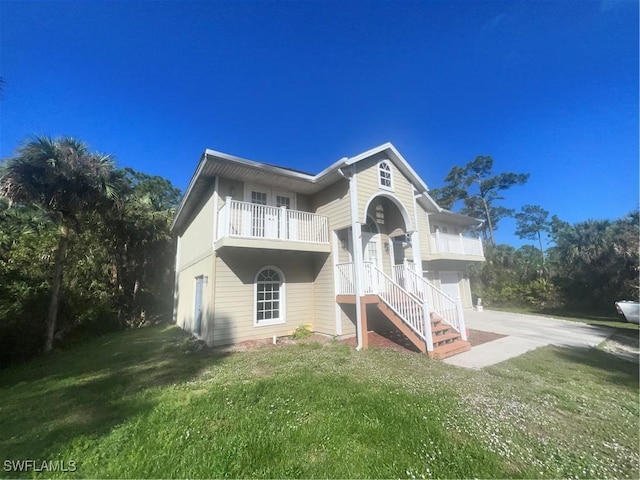 back of house featuring a balcony, a garage, and a yard